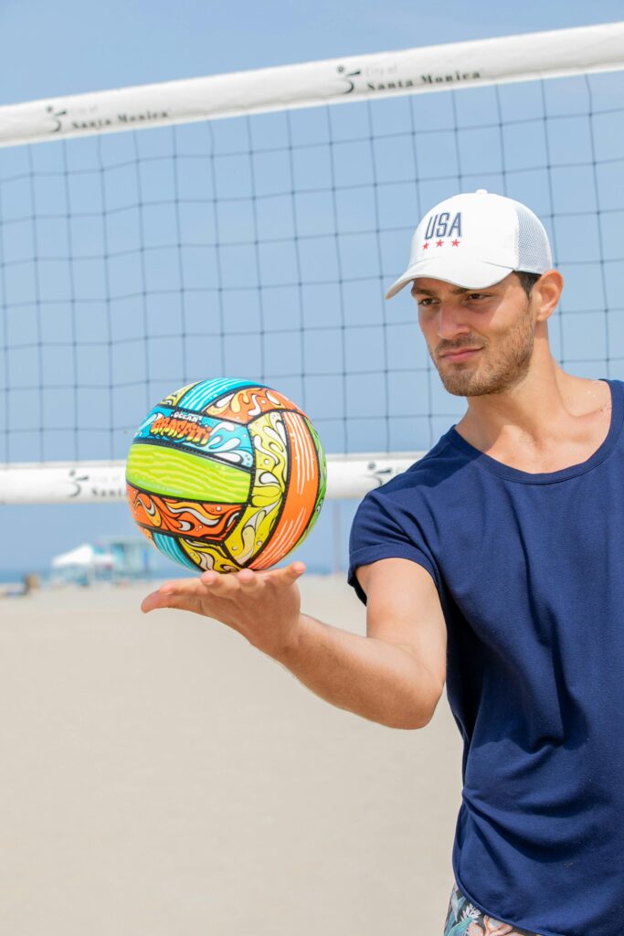 Man playing beach volleyball on a sunny day, showing a colorful ball in motion.
